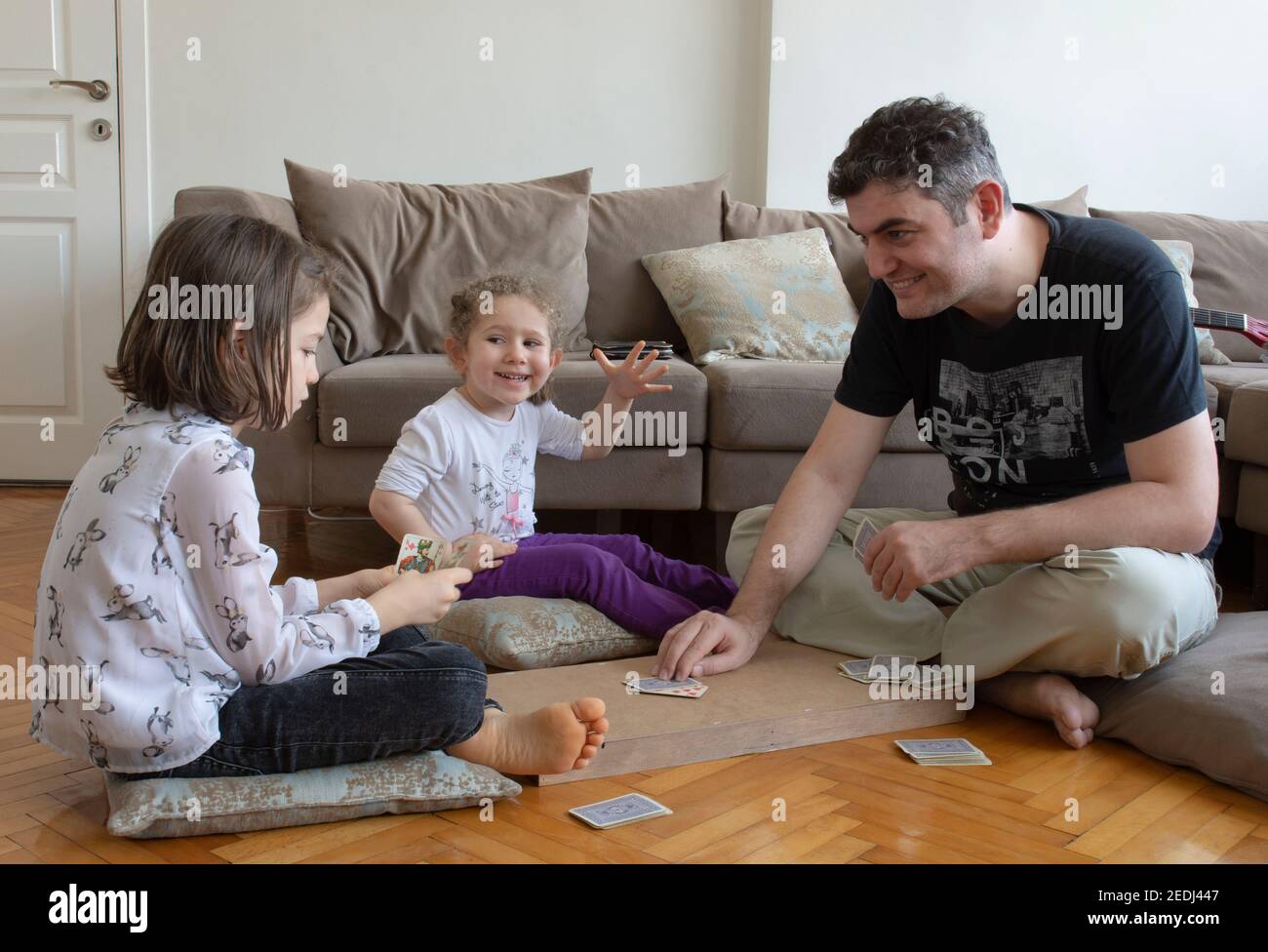 papà e bambini che giocano e imparano a giocare a carte home.stay a casa. week-end alla pandemia Foto Stock