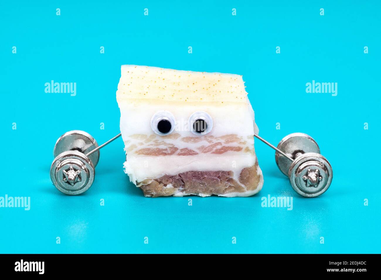 Primo piano di un personaggio divertente fatto di grasso di maiale salato sollevamento dumbbells isolato su sfondo azzurro. Concetto creativo di bruciatura dei grassi. Foto Stock