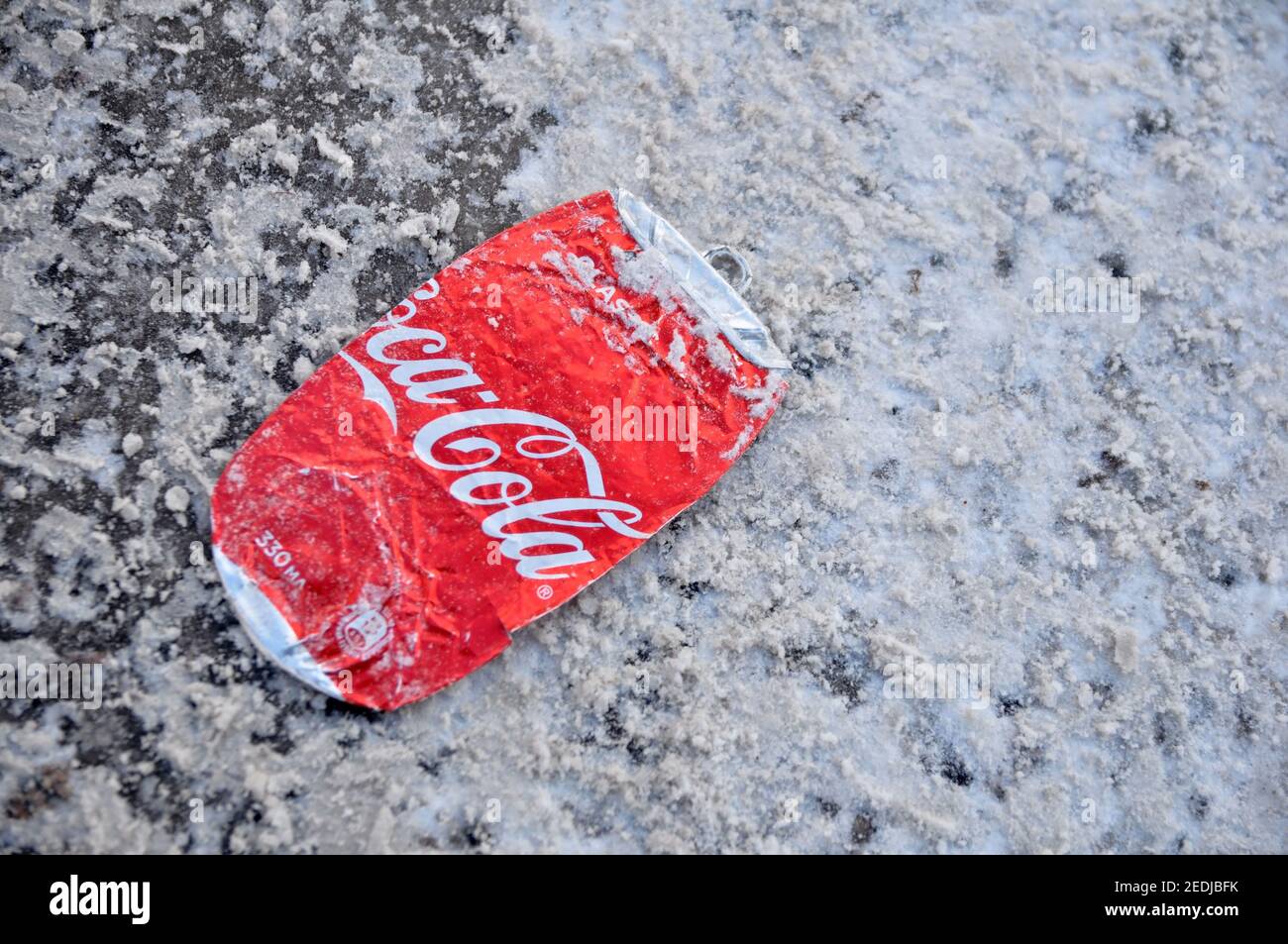 Coca-Cola può appiattire sotto le ruote delle auto su una strada invernale. Foto Stock