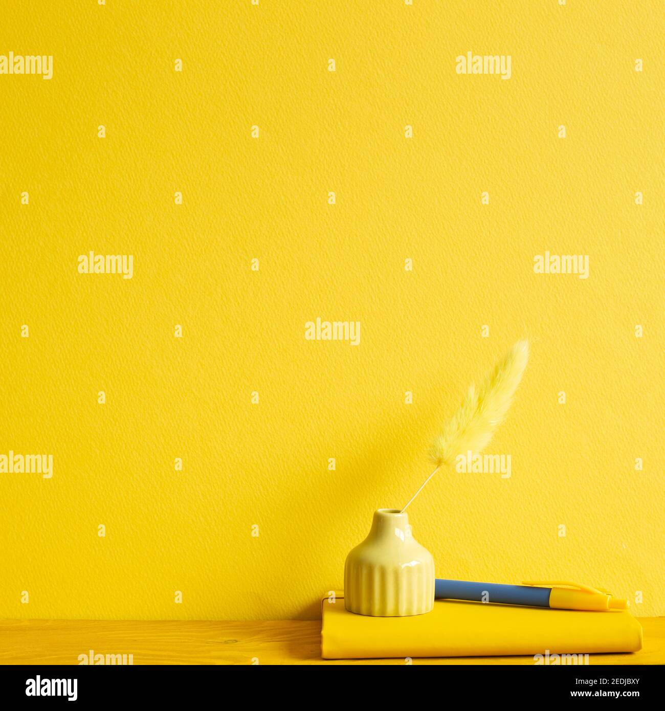 Taccuino giallo, penna, vaso di Lagurus ovatus erba su tavolo di legno. Sfondo giallo Foto Stock