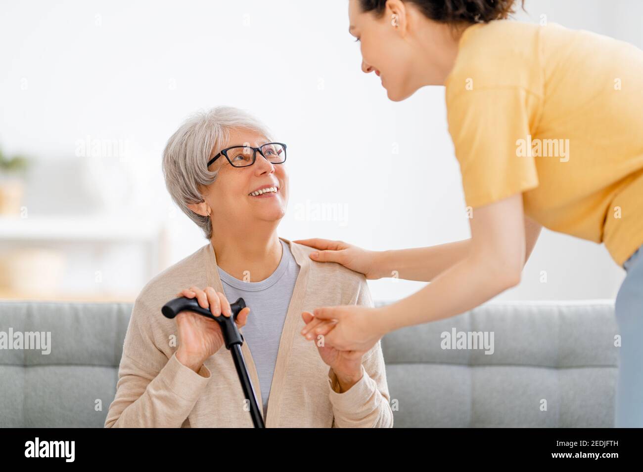 Buon paziente e caregiver che trascorrono il tempo insieme. Donna anziana che tiene canna. Foto Stock