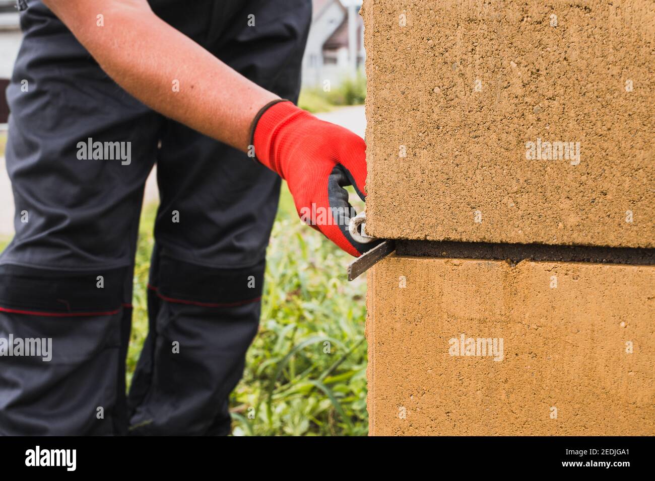 Adesivo a base di cemento per blocchi di pietra in muratura e mattoni in costruzione - un muratore professionale al lavoro Foto Stock