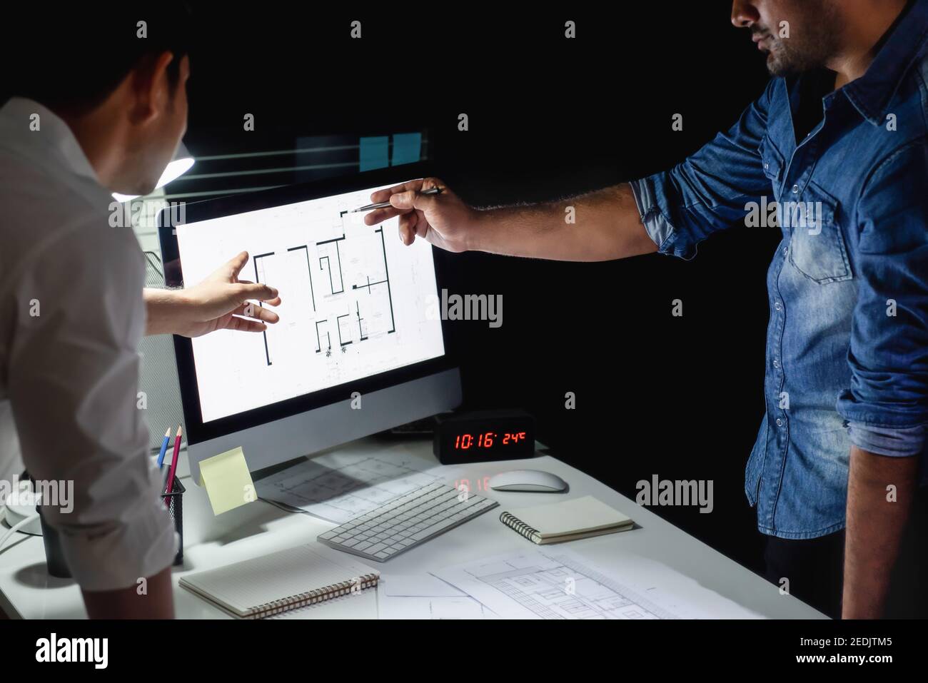 Il team di architetti asiatici rimane a tarda notte in ufficio discutere progetto di progettazione a pavimento al tavolo riunioni Foto Stock