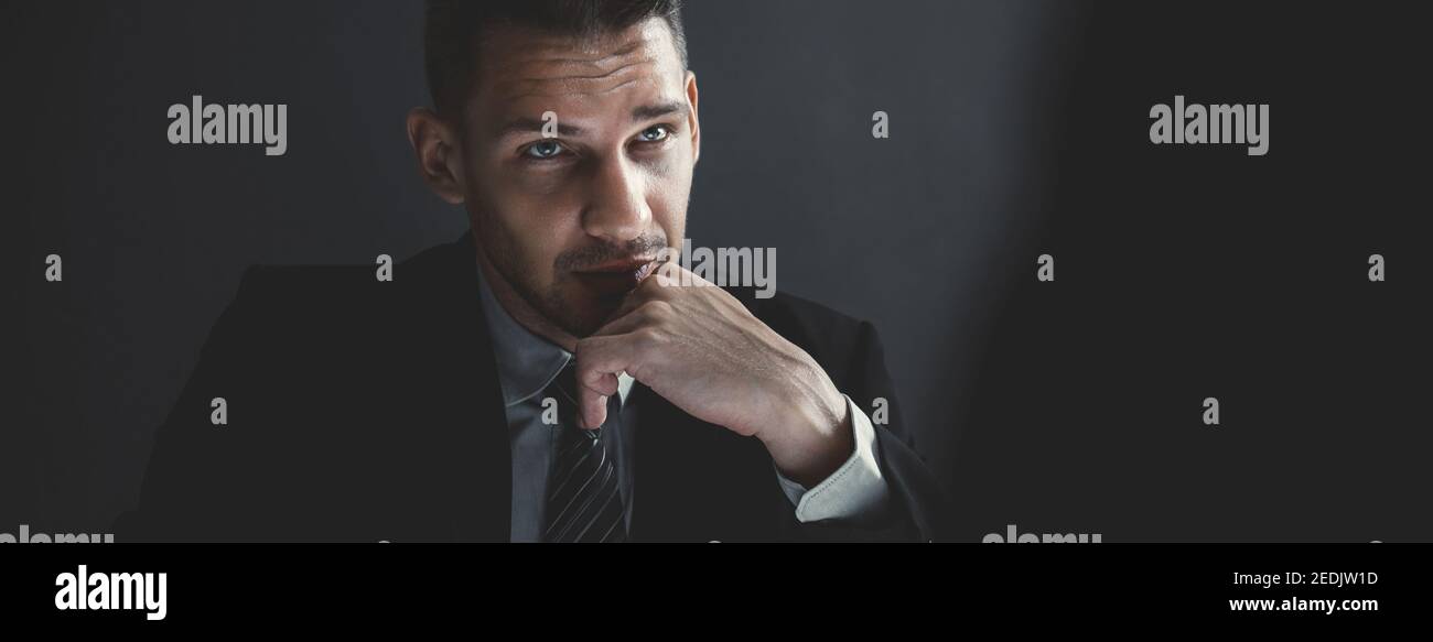 Interrogatore in ombra con faccia seria che sta fissando l'uomo criminale nella stanza di interrogatorio, bandiera panoramica Foto Stock