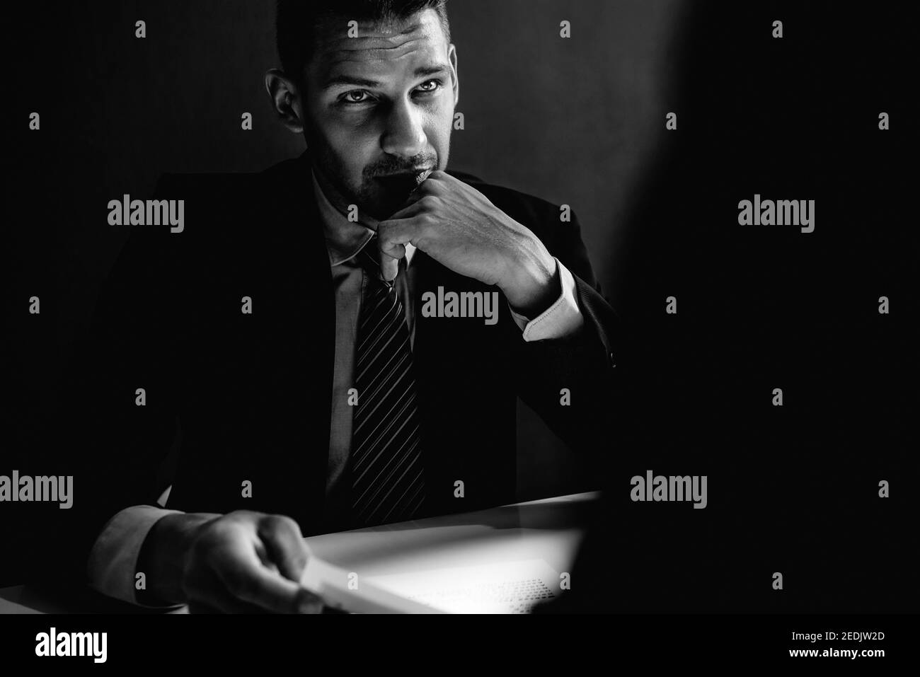 Intervista detective uomo sospetto o criminale nella stanza di interrogatorio in tono bianco e nero Foto Stock