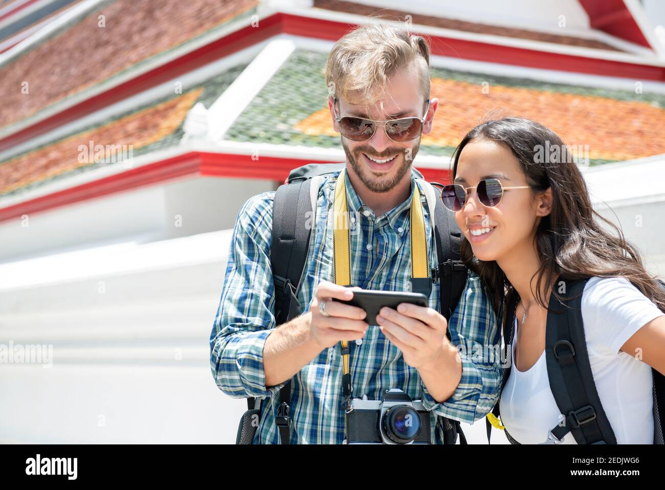 Giovane coppia turistica interracial backpackers che guarda lo schermo di smartphone trovare Direzione durante il viaggio a Bangkok Thailandia Foto Stock