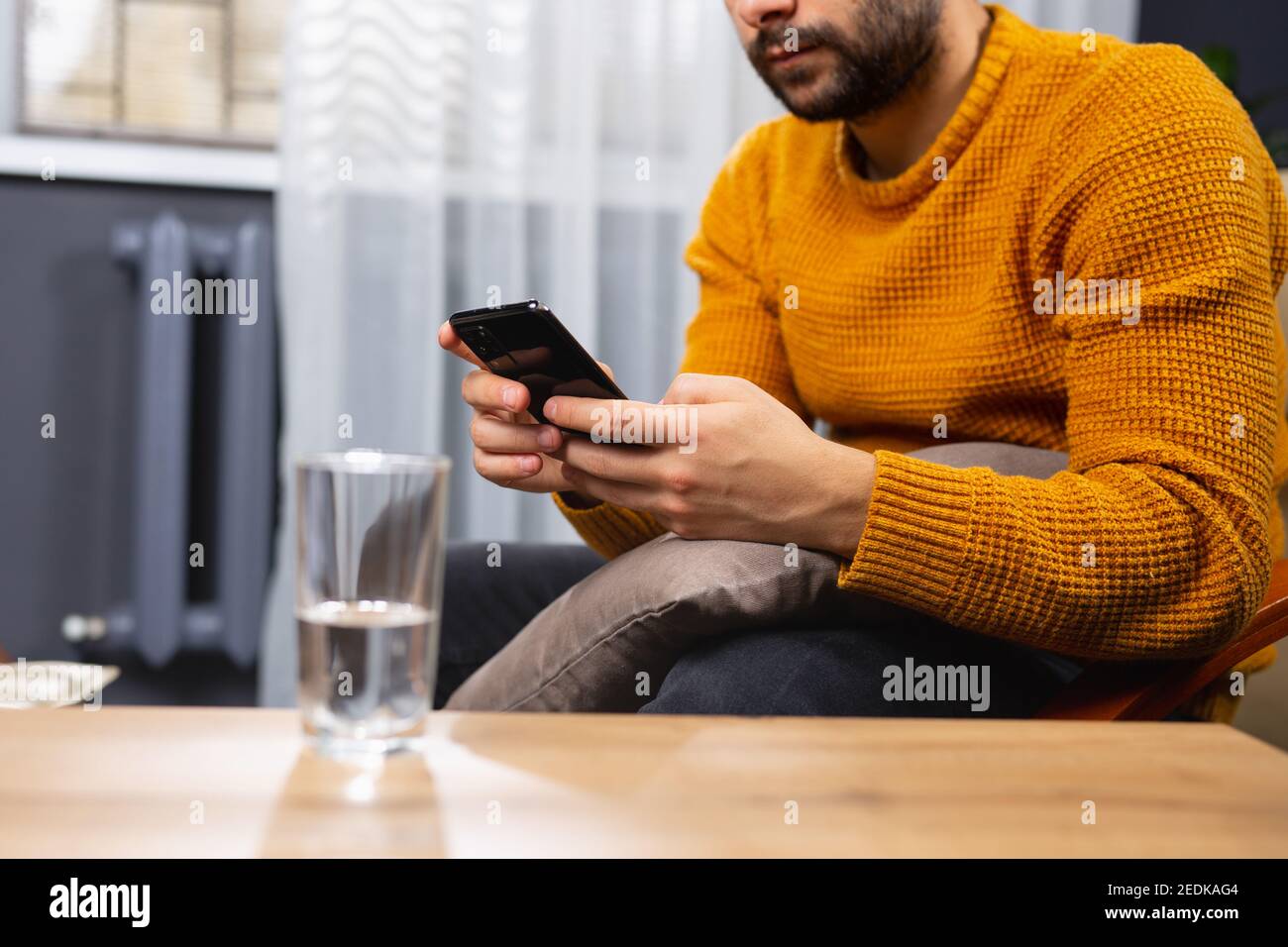 Foto ritagliata di un uomo adulto della barba, dipendente dal mondo virtuale. Sessione di psicoterapia online, un bicchiere d'acqua sul tavolo. Un uomo d'affari sta osservando Foto Stock