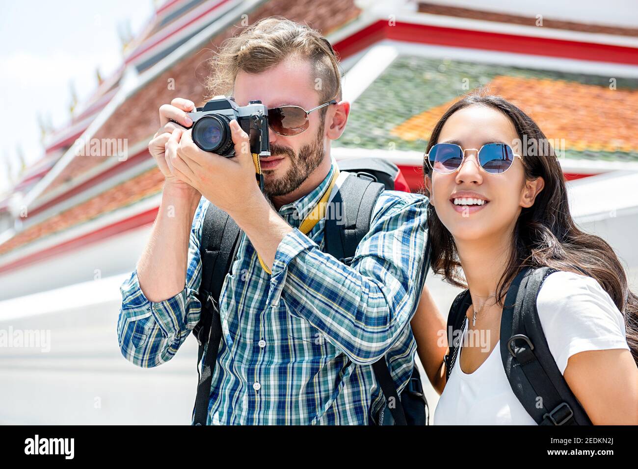 Backpackers di coppia turistica interracial che scatta foto mentre viaggia a Bangkok Thailandia con tempio tailandese sullo sfondo Foto Stock