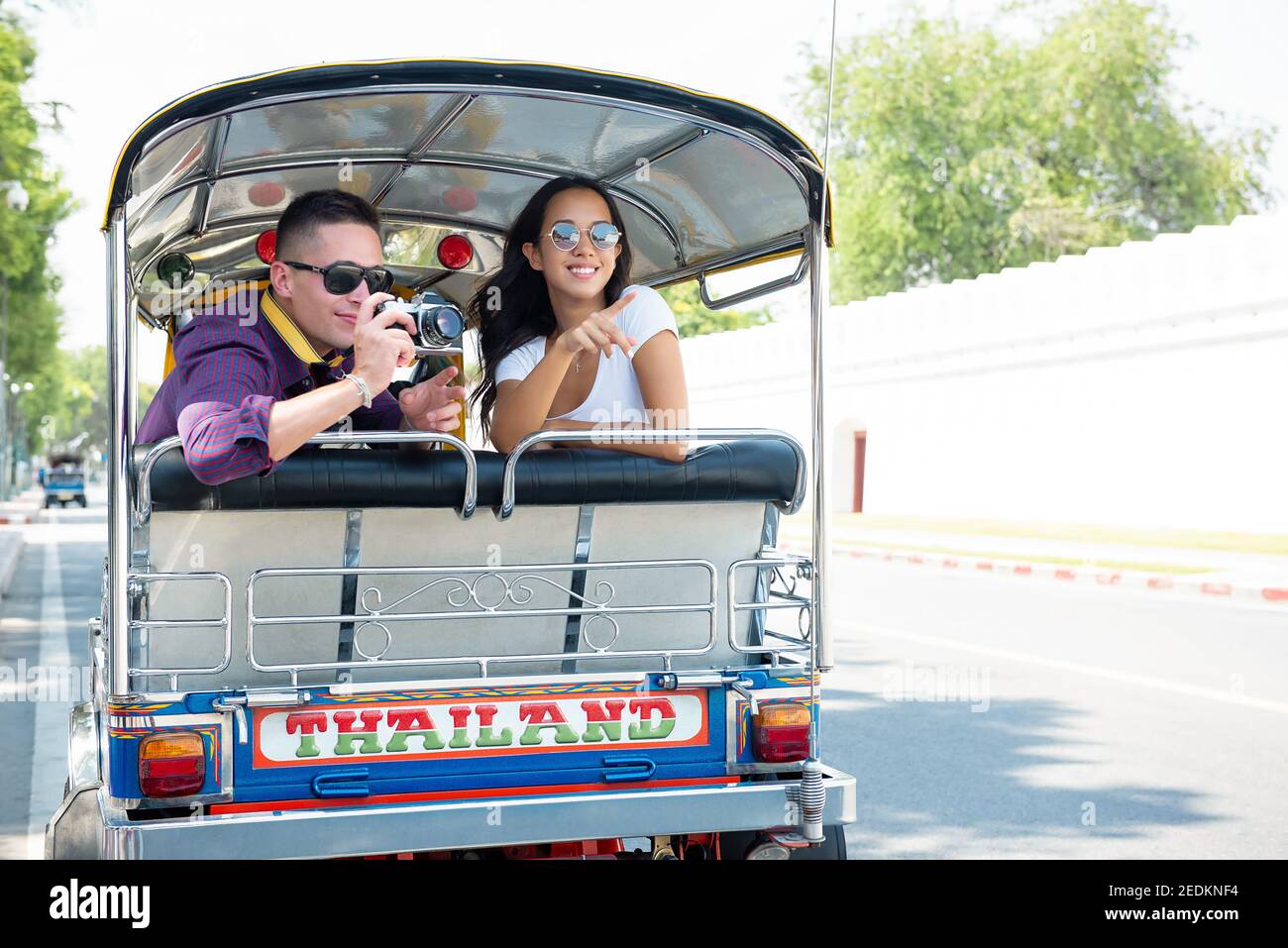 Giovani coppie di turisti che viaggiano su un taxi locale Tuk Tuk esplorando la città di Bangkok, Thailandia in vacanza estiva Foto Stock