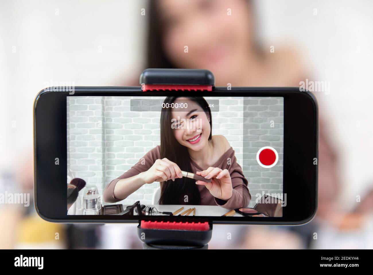 Giovane bella donna asiatica professionale di bellezza vlogger o blogger registrazione video tutorial cosmetico trucco da smartphone per condividere sui social media Foto Stock