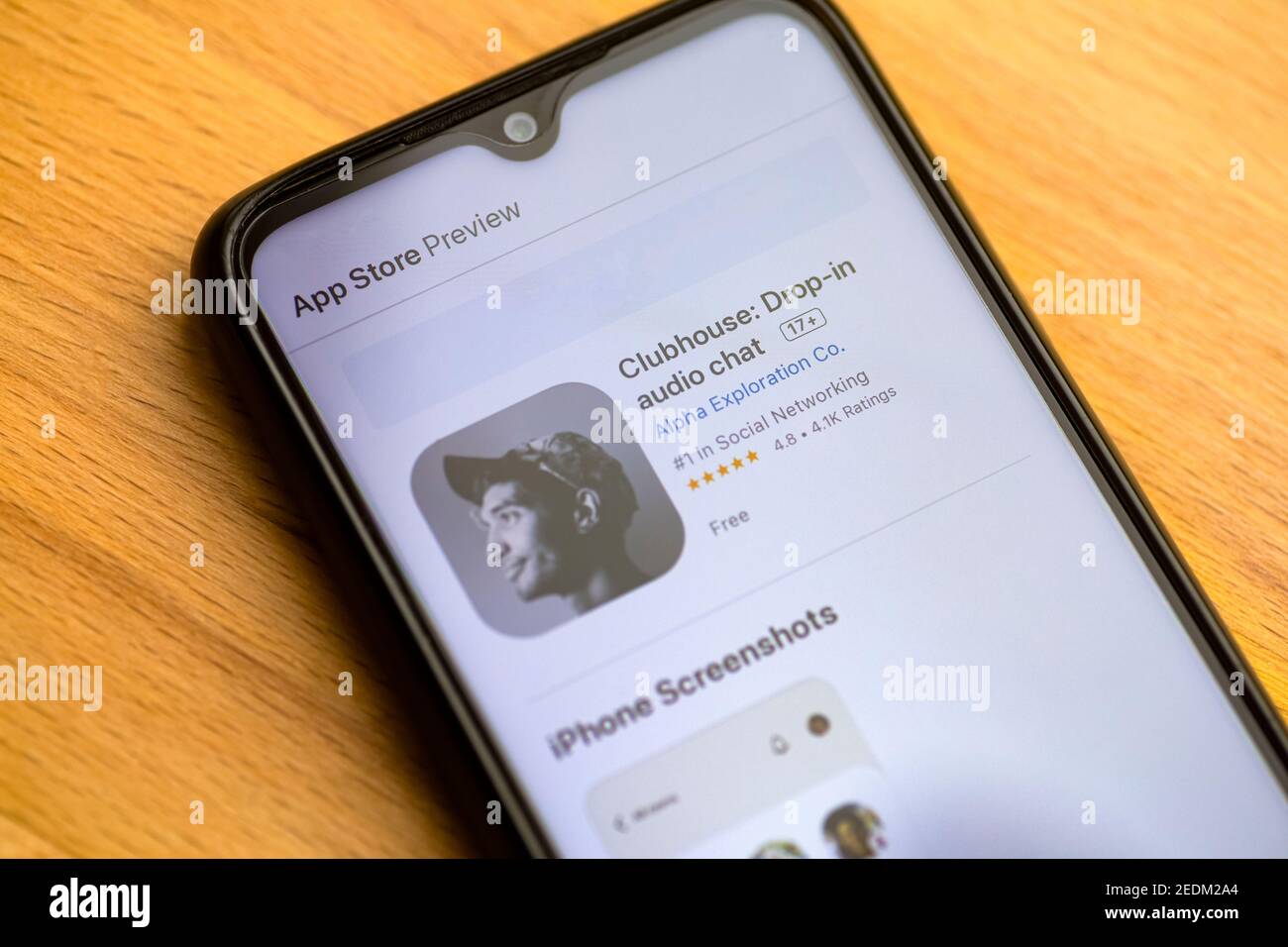 Clubhouse goccia in chat audio. Applicazione audio clubhouse per la comunicazione vocale su uno smartphone. Smartphone su uno sfondo wodden tavolo Foto Stock
