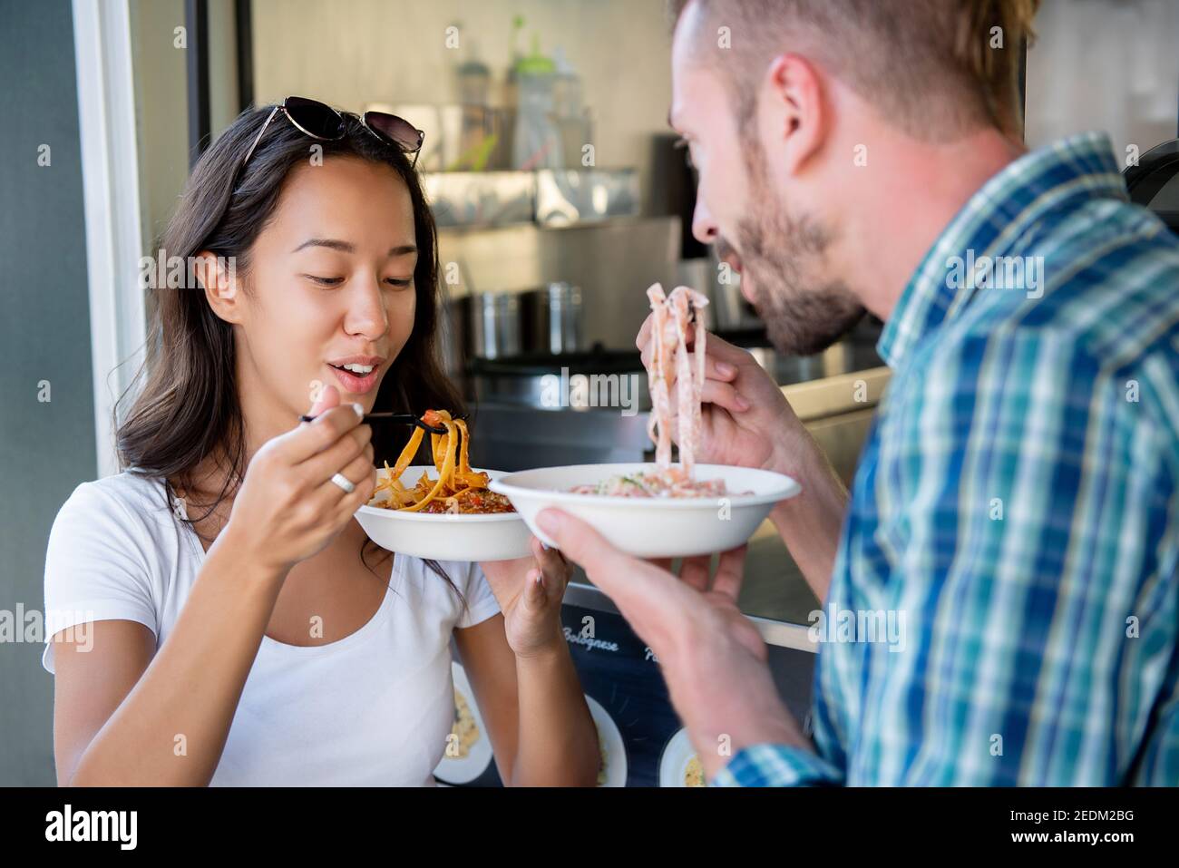 Giovane coppia interracial godendo mangiare la pasta dal camion del cibo Foto Stock