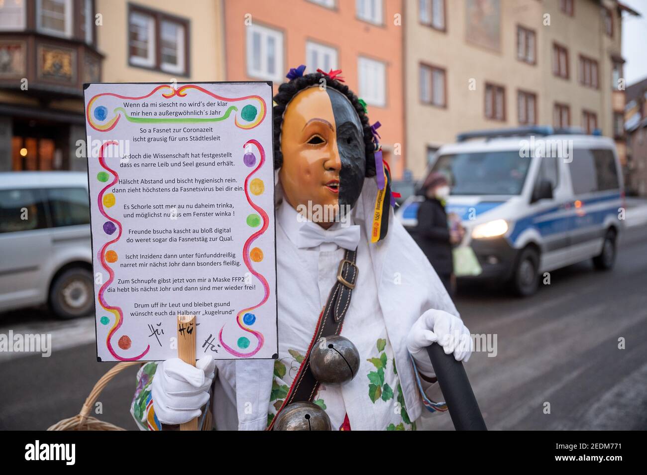 Rottweil, Germania. 15 Feb 2021. Uno sciocco si trova di fronte a una macchina della polizia il lunedì di Shrove con una poesia su 'Fasnet in Corona Time'. A causa della pandemia di Corona, il Narrensprung è stato ufficialmente annullato, ma alcuni sciocchi erano ancora sulla strada. Il Rottweiler Narrensprung è una delle attrazioni del carnevale svevo-alemannico e una delle sfilate tradizionali nel sud-ovest. Credit: Sebastian Gollnow/dpa/Alamy Live News Foto Stock