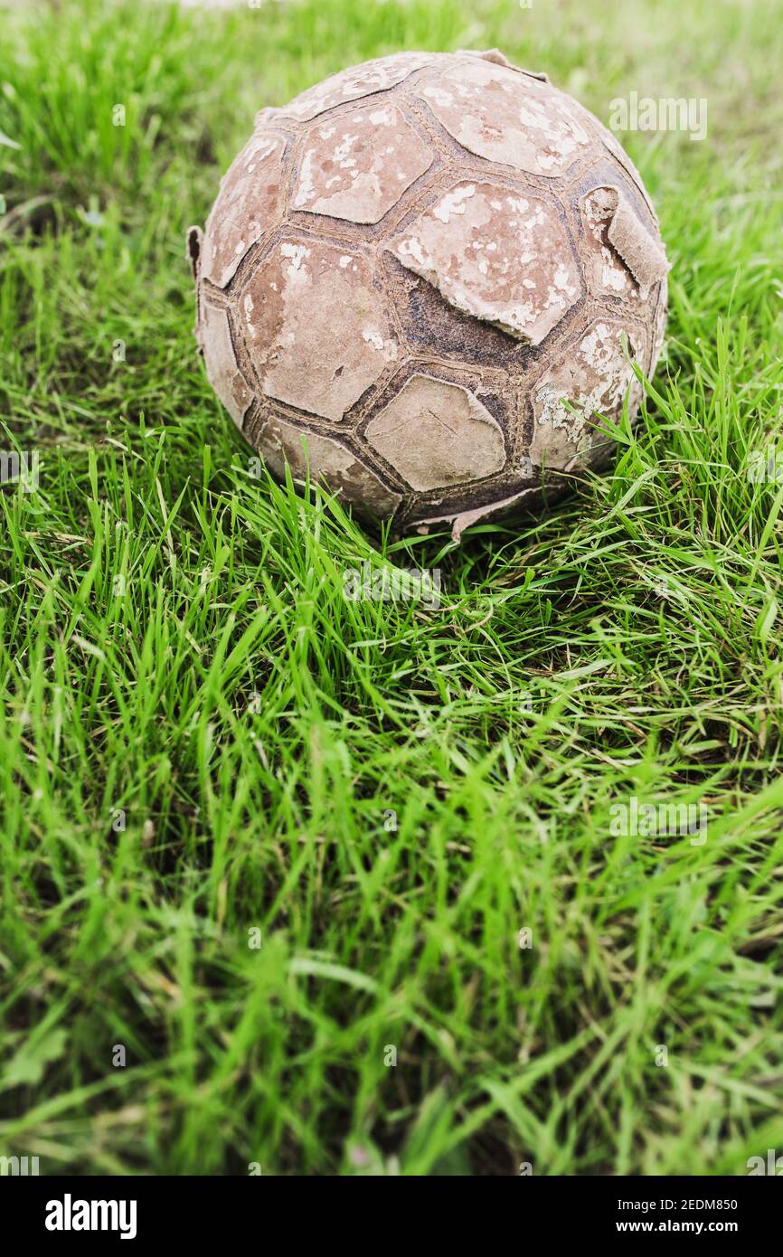 Vecchia palla da calcio in pelle vintage strappata su erba - storia del calcio Foto Stock