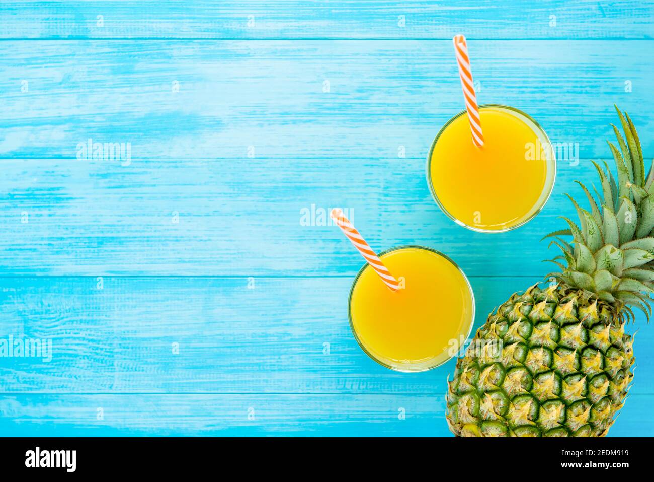 Bevande rinfrescanti per l'estate, dolce succo tropicale di ananas nei bicchieri, vista dall'alto, su sfondo di legno blu chiaro con spazio copia Foto Stock