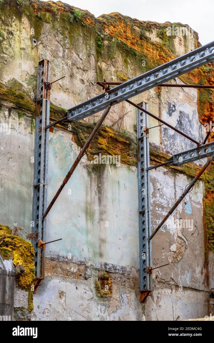 Travi di acciaio che sostengono una vecchia parete mussosa di un distrutto edificio Foto Stock
