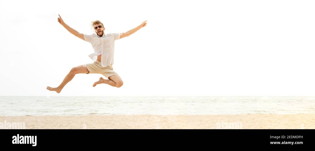 Giovane energico turista felice salto in spiaggia in vacanza estiva, divertimento e concetti di libertà, banner panoramico con spazio copia Foto Stock
