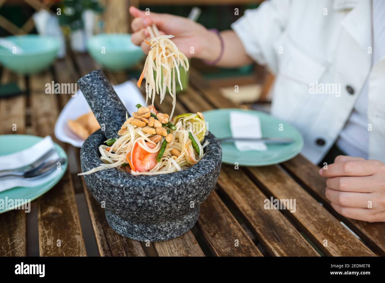 Donna che ha insalata di papaya verde denominata som tum in un Ristorante thailandese in primo piano Foto Stock