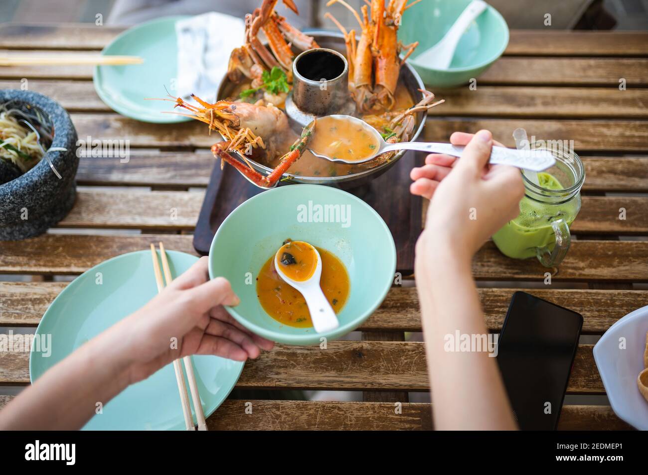 Donna che ha zuppa tailandese Tom Yum con gamberi e granchio in un ristorante vista in prima persona Foto Stock