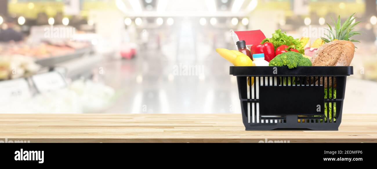 Cibo e generi alimentari nel cestino della spesa su tavolo di legno con mercato aperto sullo sfondo, banner panoramico con spazio per la copia Foto Stock