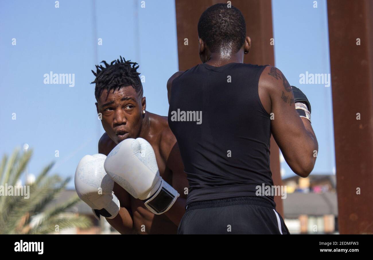 Il pugile nero professionista allena il principiante nero del boxer con i guanti di boxing una classe di boxing all'aperto in una giornata soleggiata mentre entrambi sudano. Concetto di boxe. Foto Stock