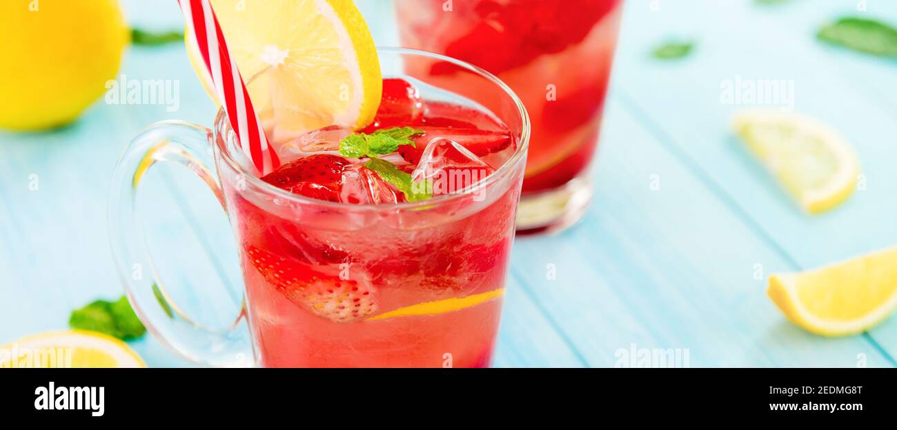 Bevande rinfrescanti colorate per l'estate, succo di limonata di fragole fredde con cubetti di ghiaccio in glasse guarnito con limone fresco affettato, banner panoramico Foto Stock
