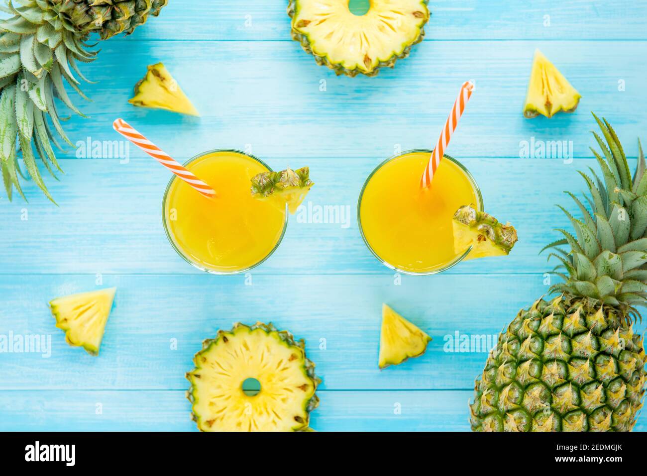 Bevanda rinfrescante per l'estate, dolce succo tropicale di ananas nei bicchieri, vista dall'alto, su sfondo di legno blu chiaro Foto Stock