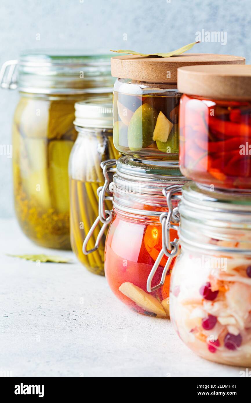 Verdure sottaceto o fermentate fatte in casa - crauti, aglio selvatico, peperoncino, sottaceti, pomodori sottaceto e olive in vasetti di vetro. Foto Stock