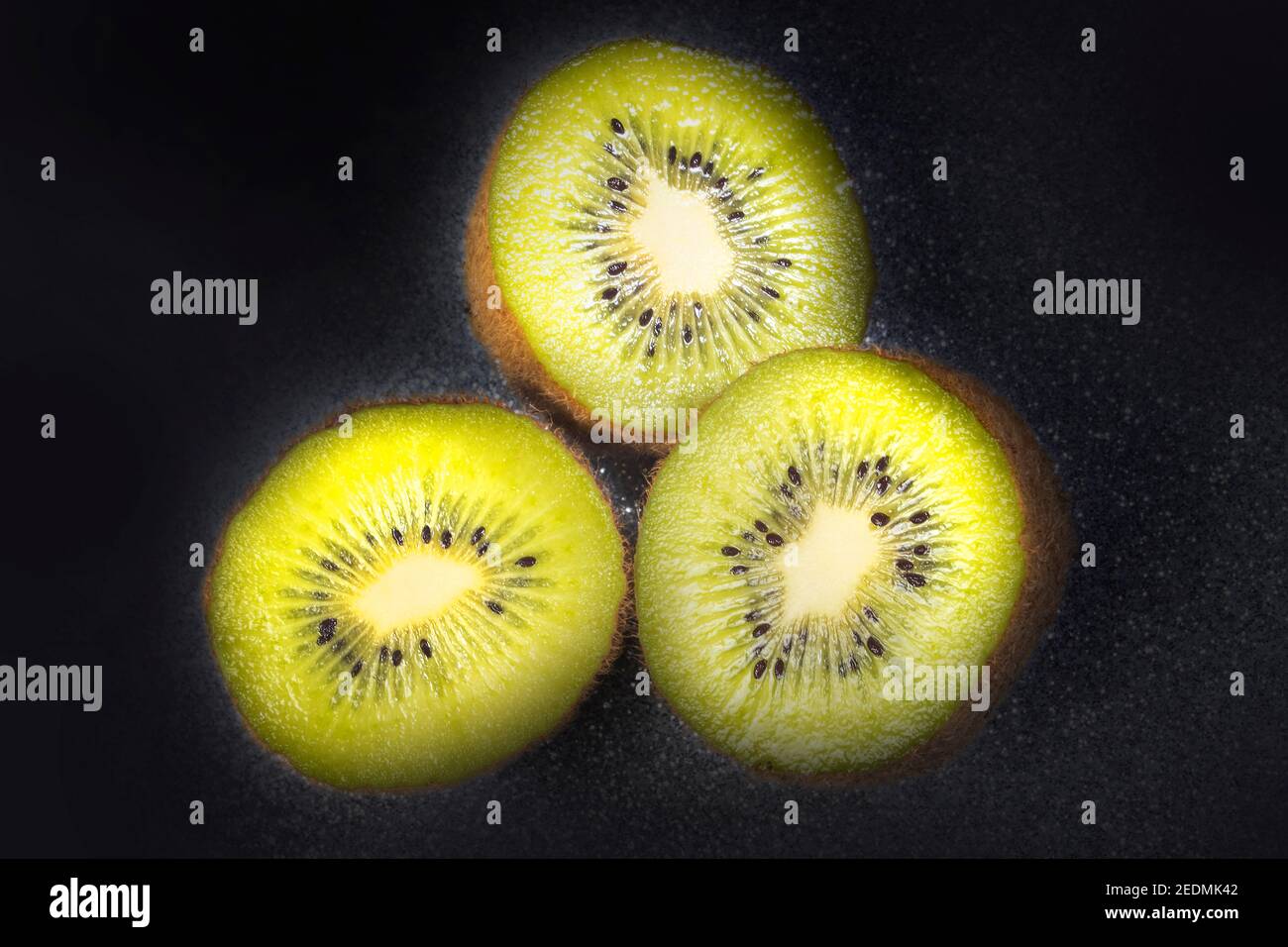 Primo piano Macro Photo of Three Vivid Kiwi Slices . Su asfalti scuri come sfondo. Studio foto. Foto Stock