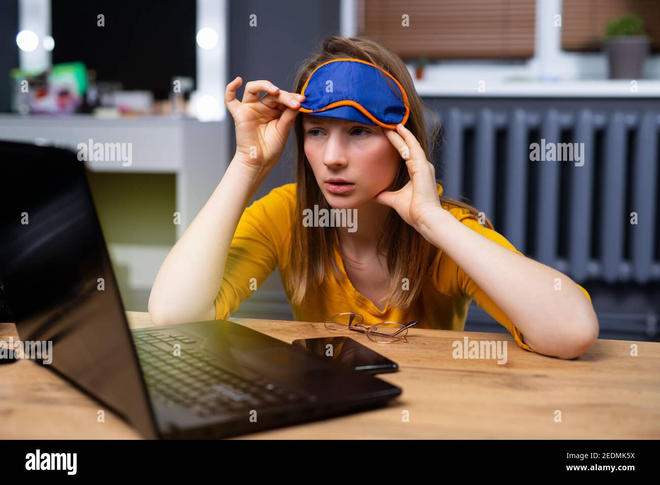 Bella giovane, caucasica, bionda-capelli, internet addicted donna che lavora annoiato, insonne e stanca Foto Stock