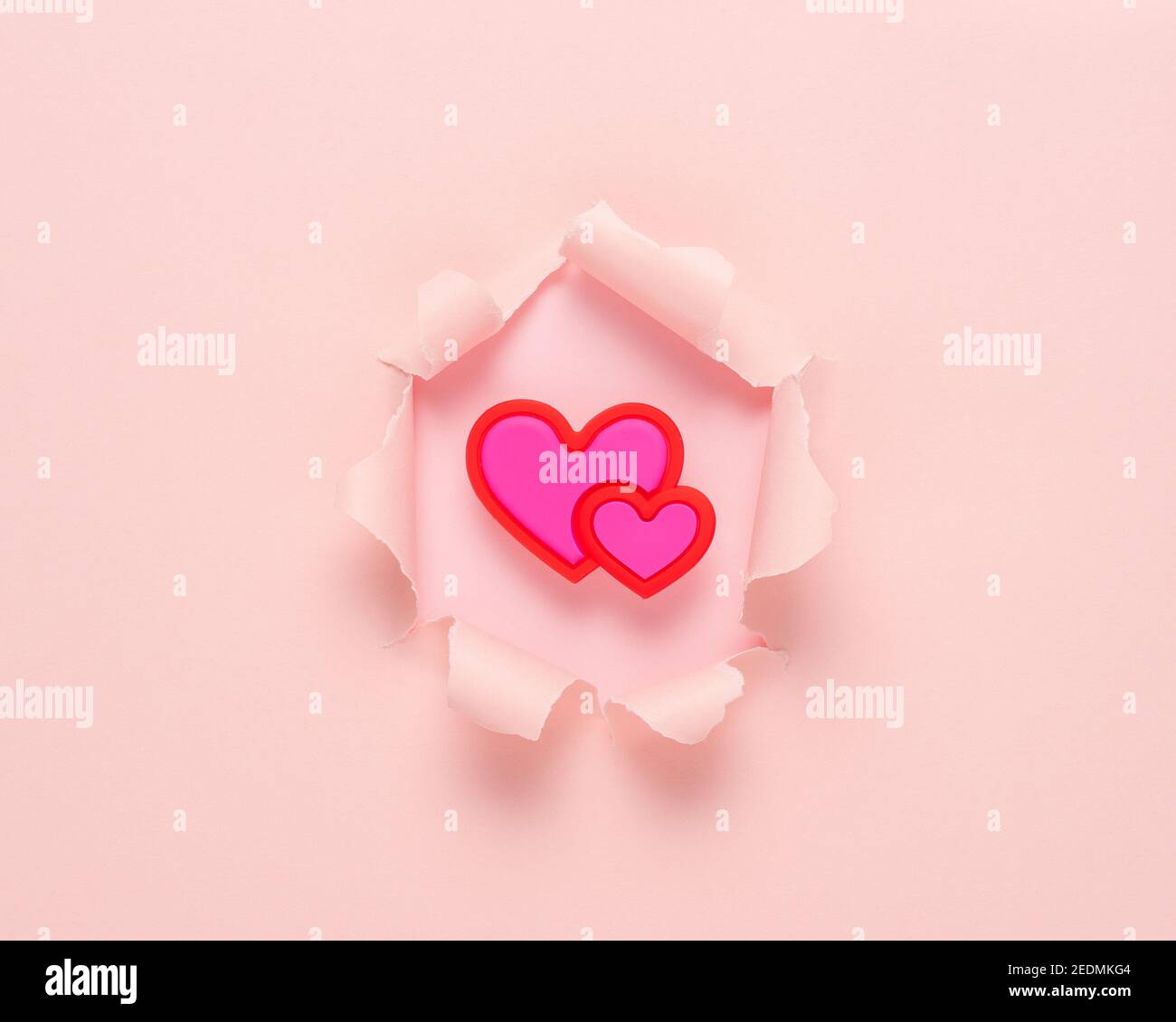 Carta strappata rosa brillante con cuore su sfondo rosa. Concetto astratto di amore minimo. Foto Stock