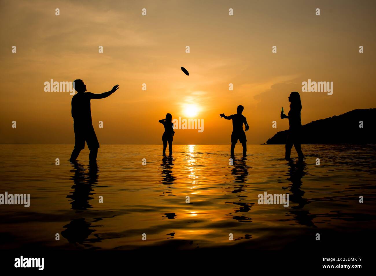 Silhouette di persone che giocano in spiaggia al tramonto durante vacanze estive Foto Stock