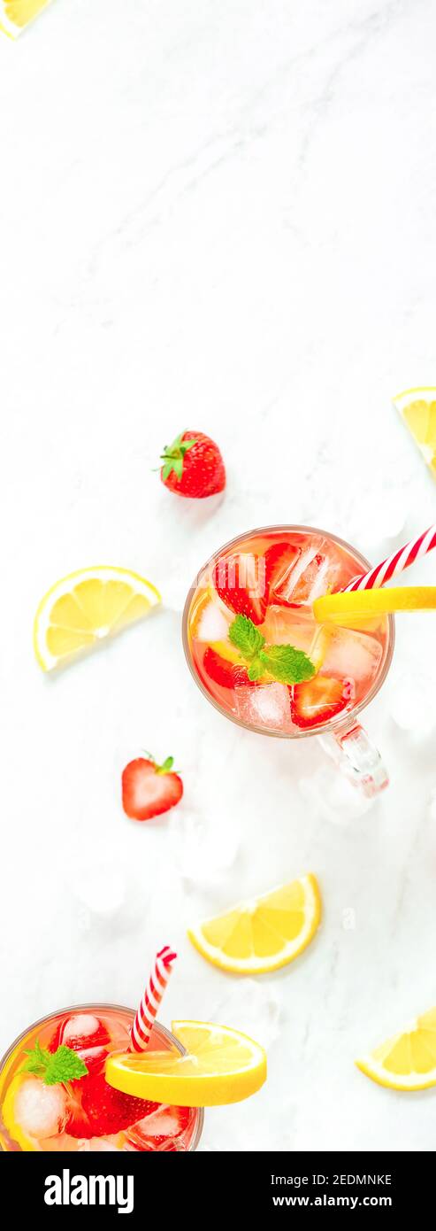Bevande rinfrescanti colorate per l'estate, succo di limonata di fragole fredde nei bicchieri con cubetti di ghiaccio, bandiera laterale vericale sfondo vista dall'alto Foto Stock