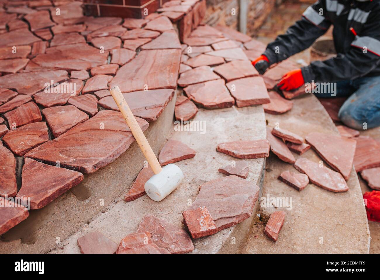 Mosaico di pietra per la terrazza della casa - posa delle piastrelle all'esterno - lavoro professionale della piastrella Foto Stock