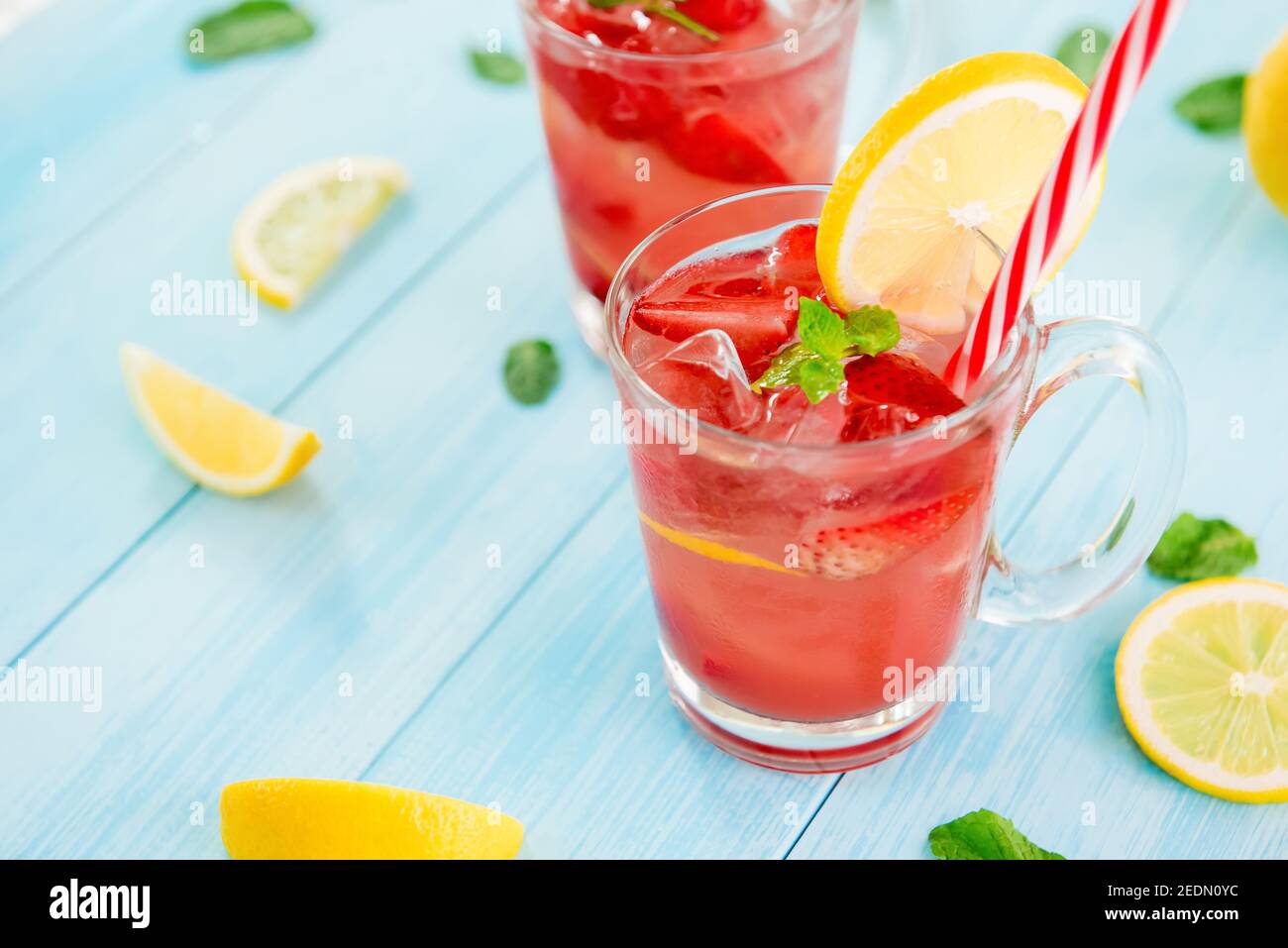Bevande rinfrescanti e colorate per l'estate, dolce freddo e sour succo di limonata di fragole con cubetti di ghiaccio nei bicchieri guarniti con fettina di limone Foto Stock