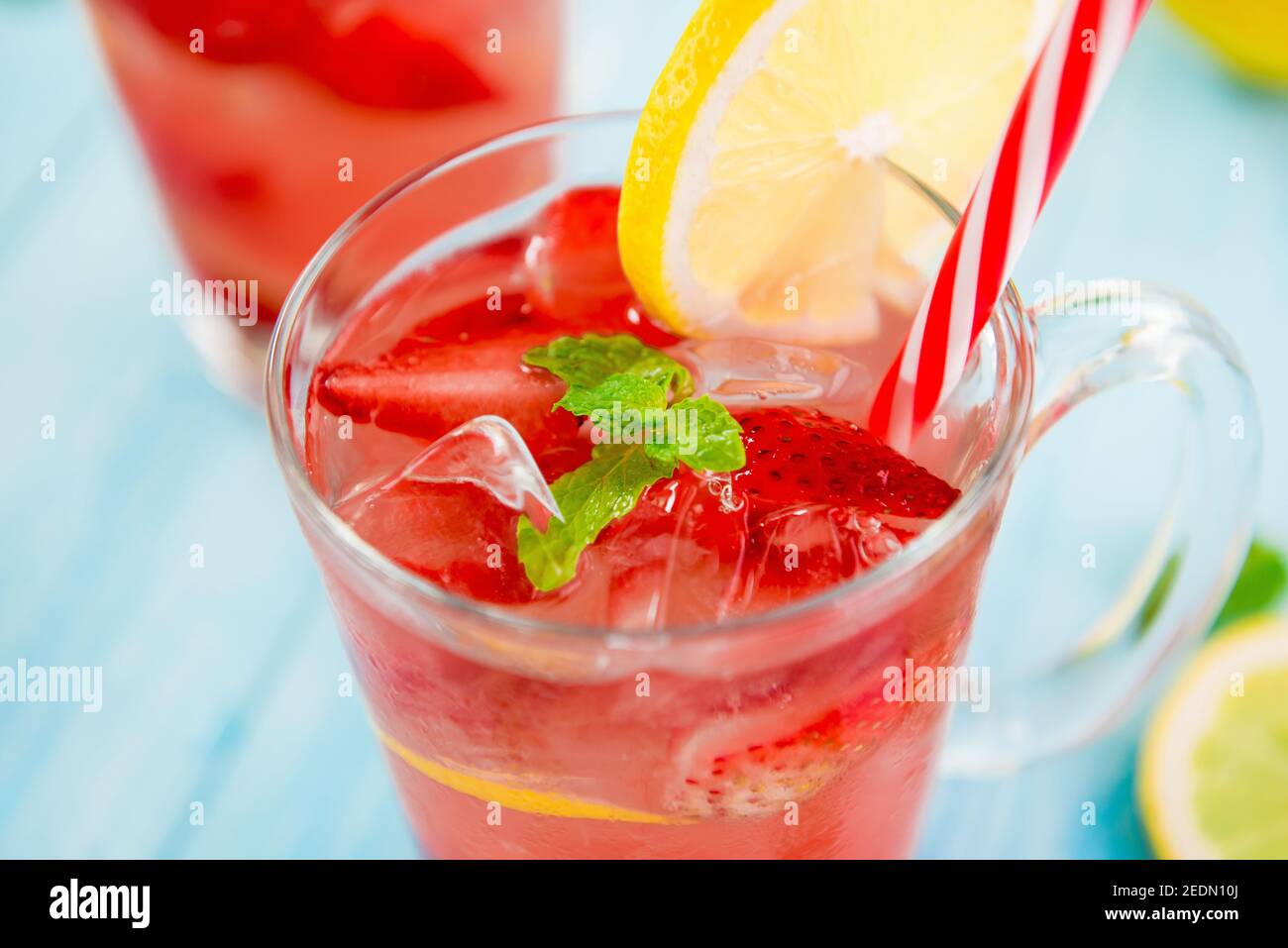 Bevande rinfrescanti e colorate per l'estate, dolce freddo e sour succo di limonata di fragole con cubetti di ghiaccio nei bicchieri guarniti con fettina di limone Foto Stock