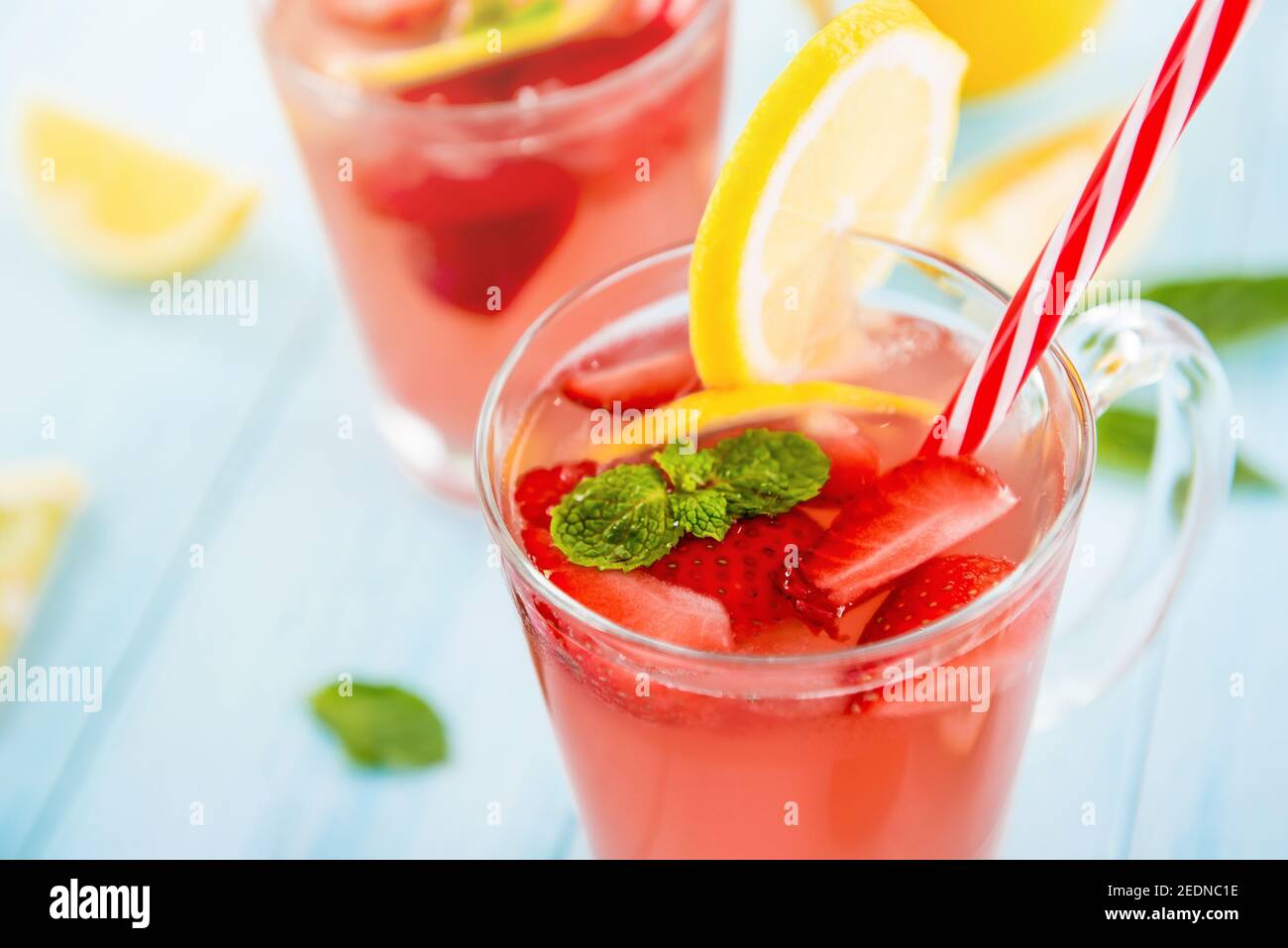 Bevande rinfrescanti colorate per l'estate, dolce freddo e sour succo di limonata di fragole nei bicchieri guarniti con limoni a fette Foto Stock