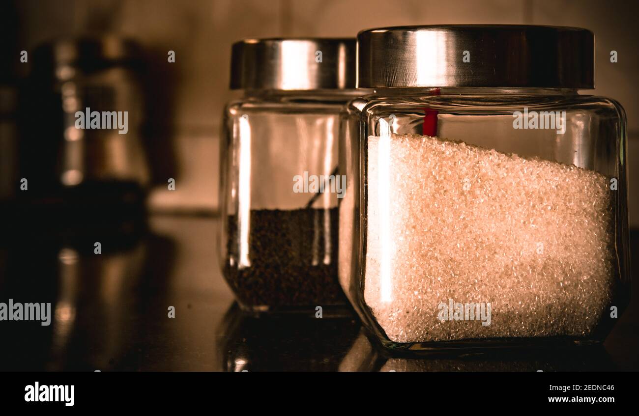 Contenitori di vetro contenenti zucchero di canna bianco e polvere di tè Foto Stock