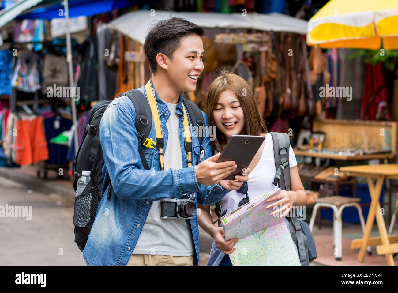 Coppie asiatiche turisti backpackers utilizzando tablet per trovare la posizione durante il viaggio in vacanza a Khao San Road, Bangkok, Thailandia Foto Stock