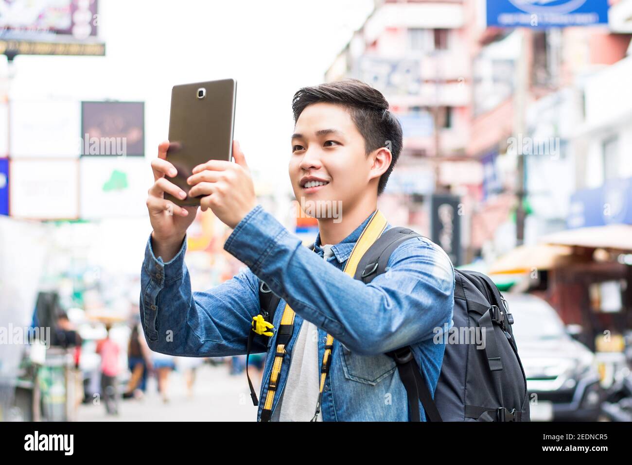 Giovane uomo asiatico turista zaino in spalla scattare foto con il computer tablet mentre viaggia in vacanza in Khaosan strada Bangkok, Thailandia Foto Stock