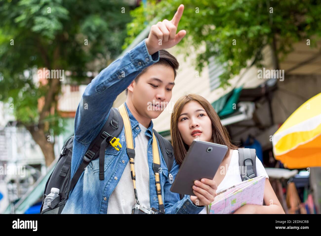 Coppie asiatiche turisti backpackers utilizzando tablet per trovare la posizione durante il viaggio in vacanza a Khao San Road, Bangkok, Thailandia Foto Stock