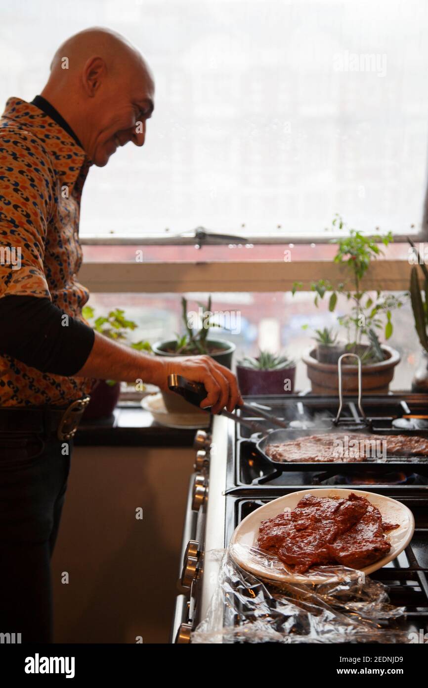 Uomo che grigliano carne su stufa Foto Stock