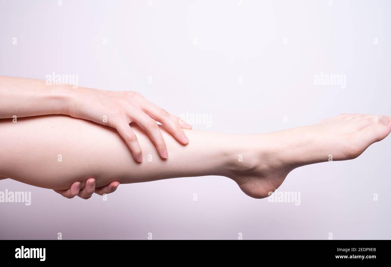 massaggio dei muscoli delle gambe con le mani, dolore alle gambe Foto Stock