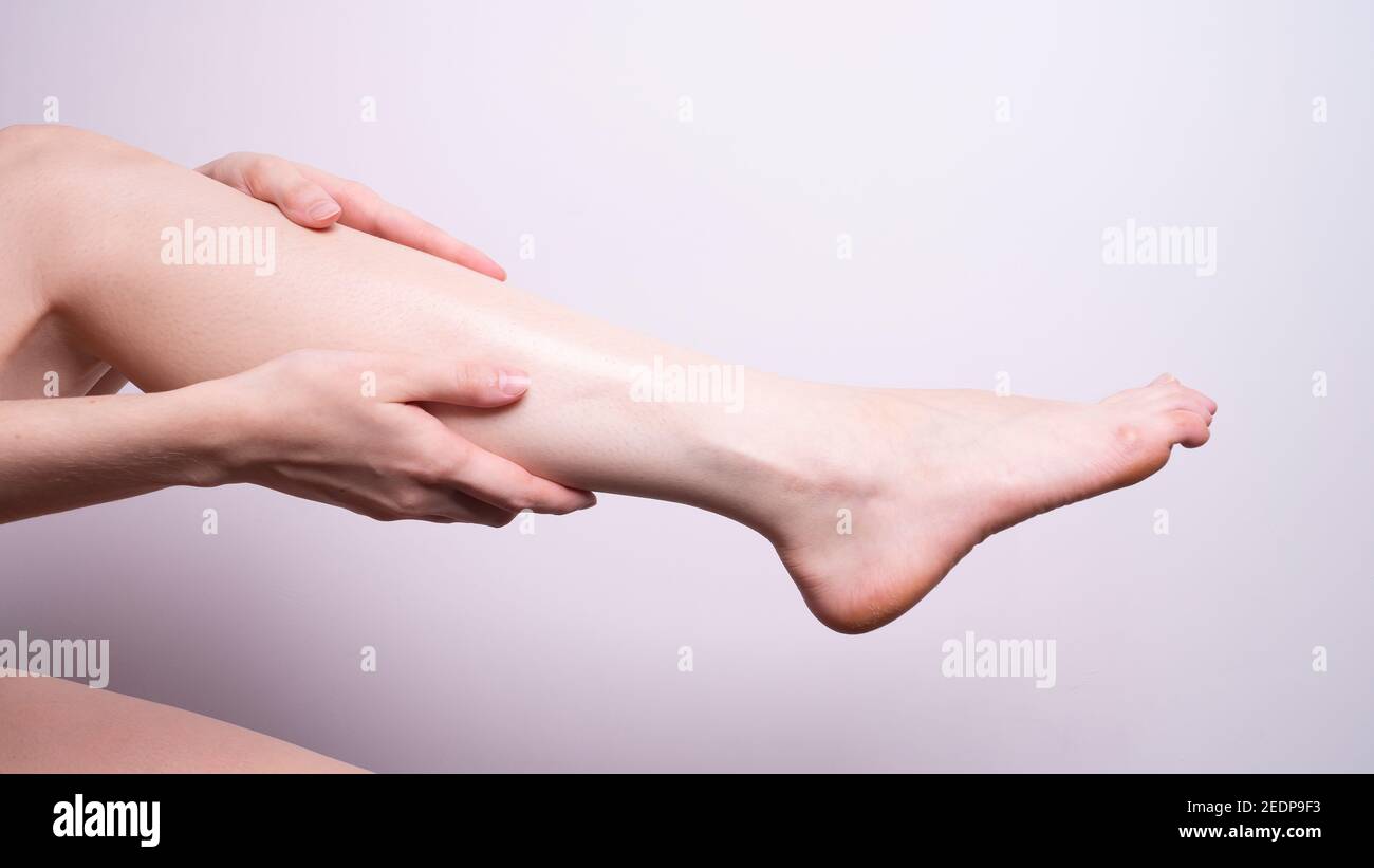 massaggio dei muscoli delle gambe con le mani, dolore alle gambe Foto Stock