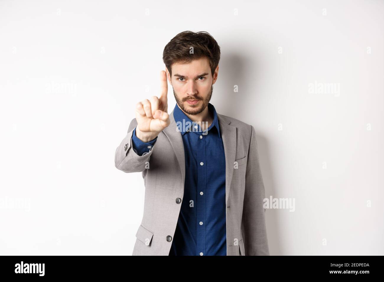Ascoltami. Serio uomo ceo manager mostrando un dito, scolding o dicendo di fermarsi, dire no, tenere a destra lì segno, in piedi su sfondo bianco Foto Stock