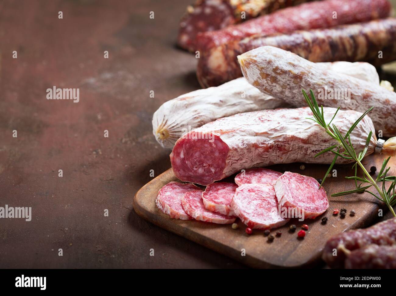 Vari tipi di salame, prosciutto e salsicce su tavola di legno Foto Stock