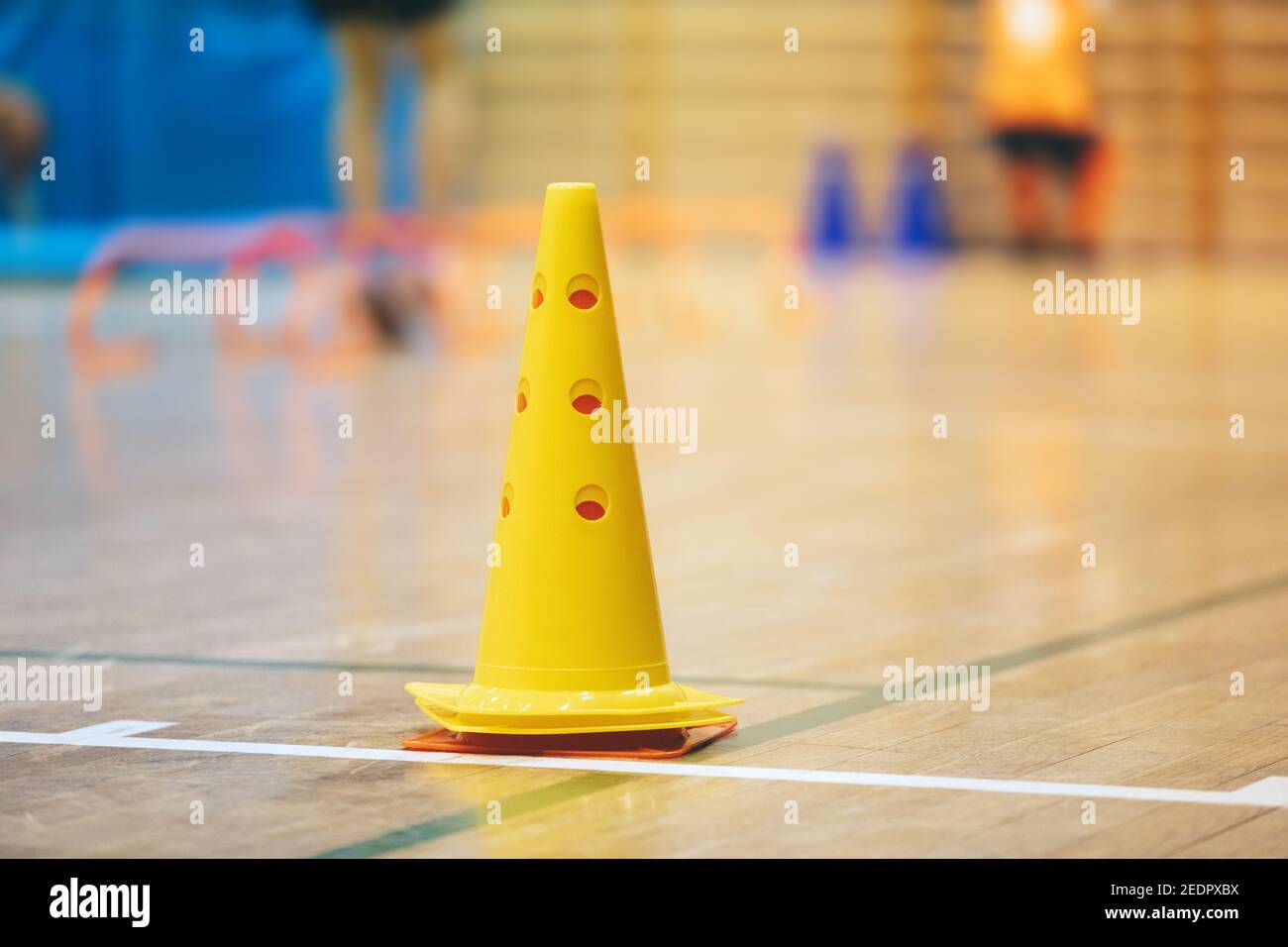 Cono di allenamento sportivo giallo su superficie lucida del pavimento sportivo in legno. Calcio al coperto, campo di allenamento di pallacanestro Foto Stock