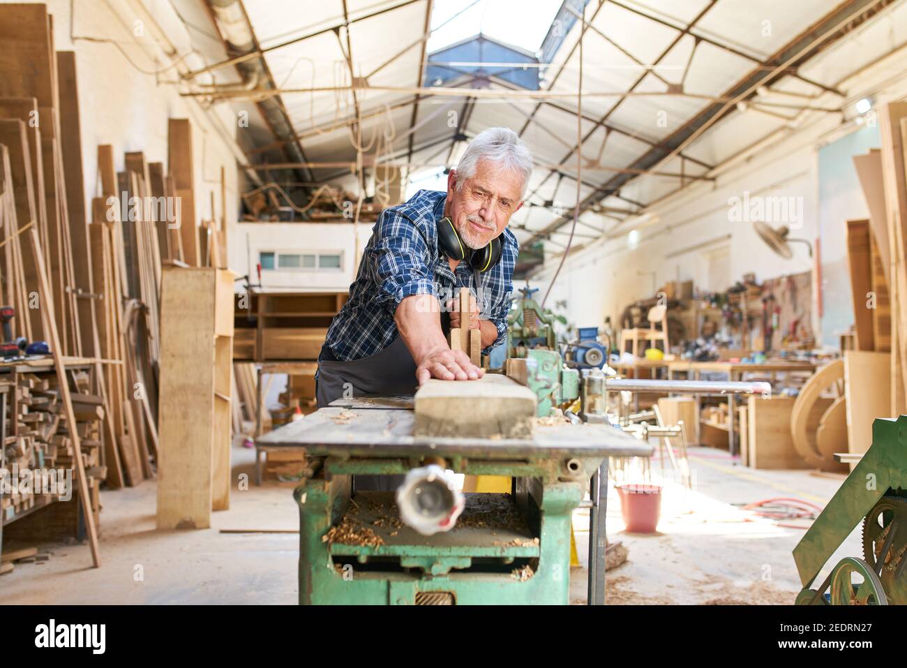 Artigiano anziano lavora sulla pialla nel laboratorio di Falegnameria Foto Stock