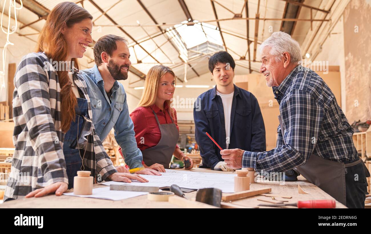 Master nella formazione degli apprendisti carpentieri in una riunione in officina Foto Stock