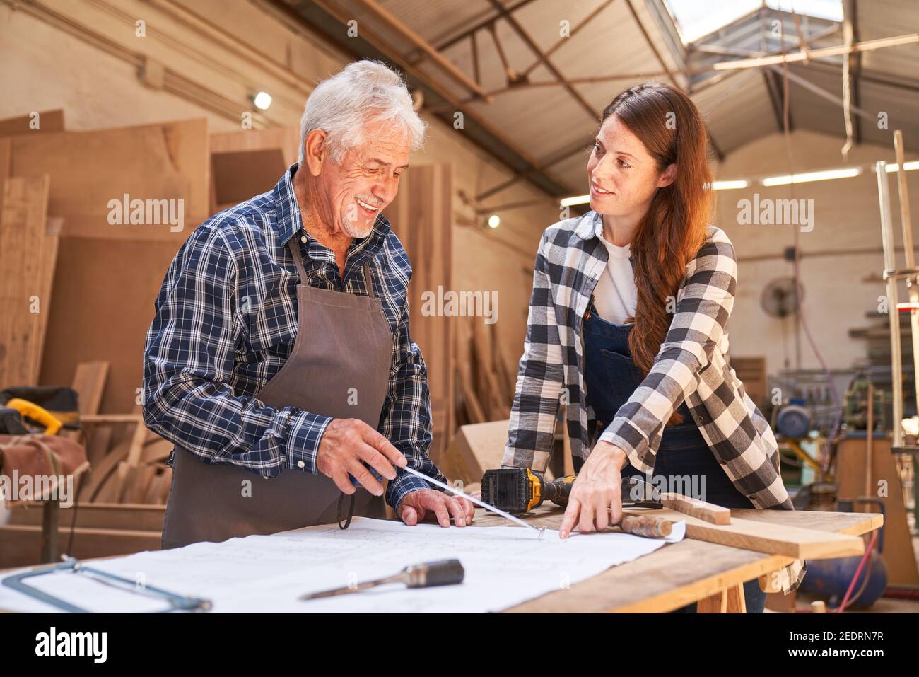 Artigiano senior come allenatore e donna come falegname apprendista nella falegnameria Foto Stock